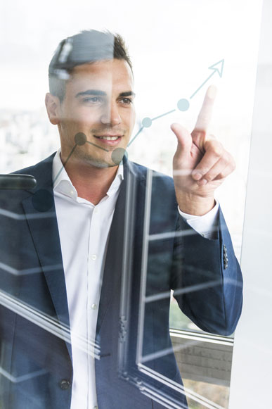 smiling-young-businessman-pointing-finger-at-increasing-graph-on-transparent-glass